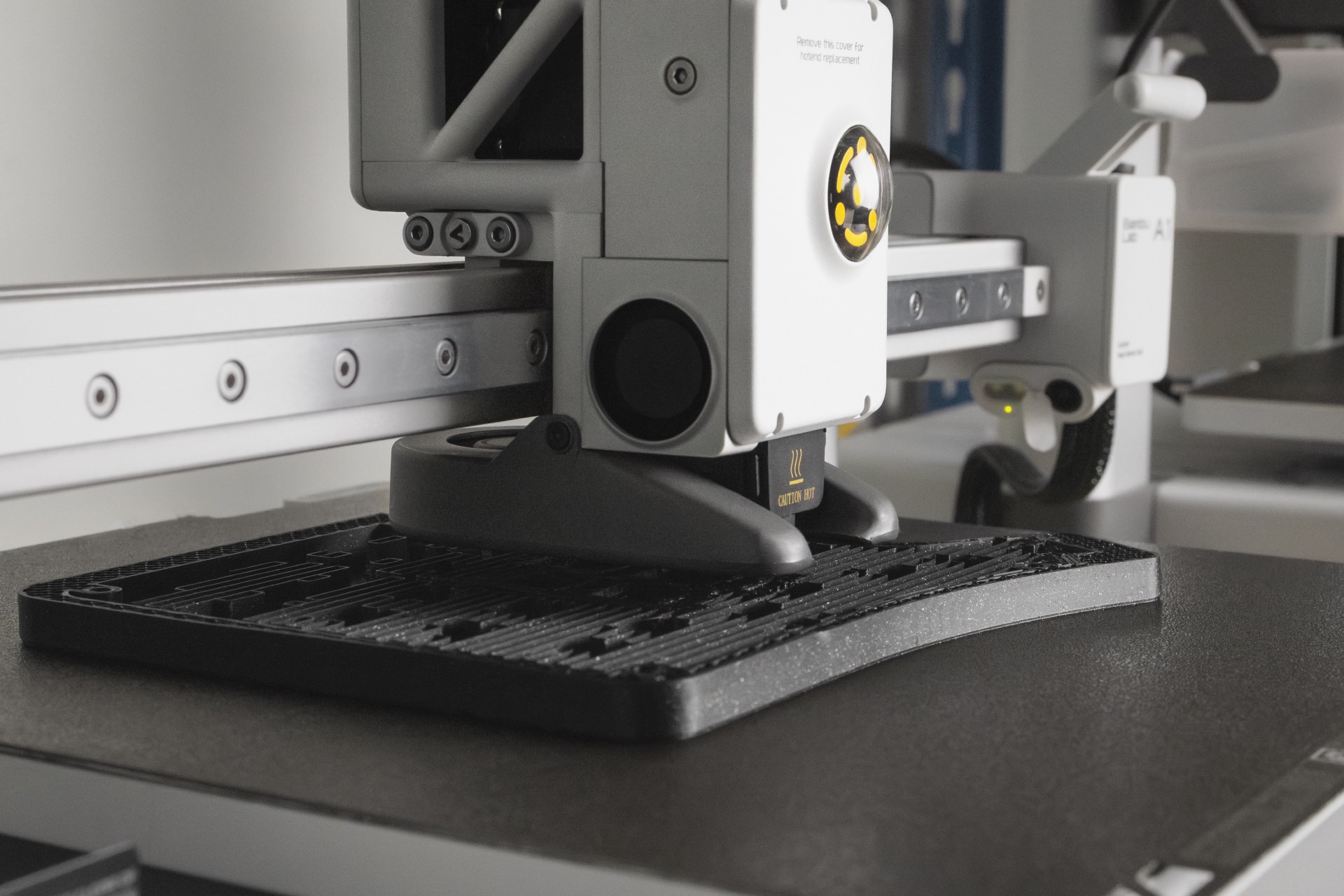 Крупный план 3D-принтера, который слой за слоем печатает скульптурный чёрный корпус Phenom